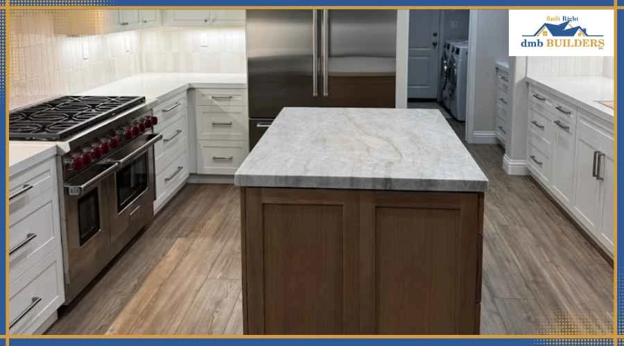 Modern kitchen with white cabinetry, stainless steel range, and a marble-topped island at center.